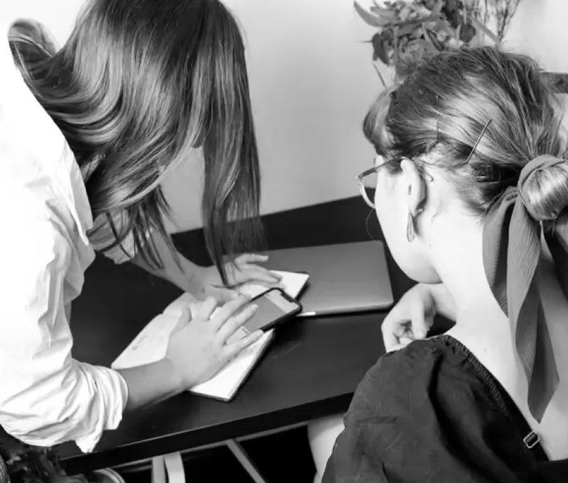 Two women reviewing designs on a cell phone
